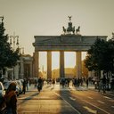 Menschen gehen bei Sonnenaufgang vor dem Brandenburger Tor in Berlin entlang