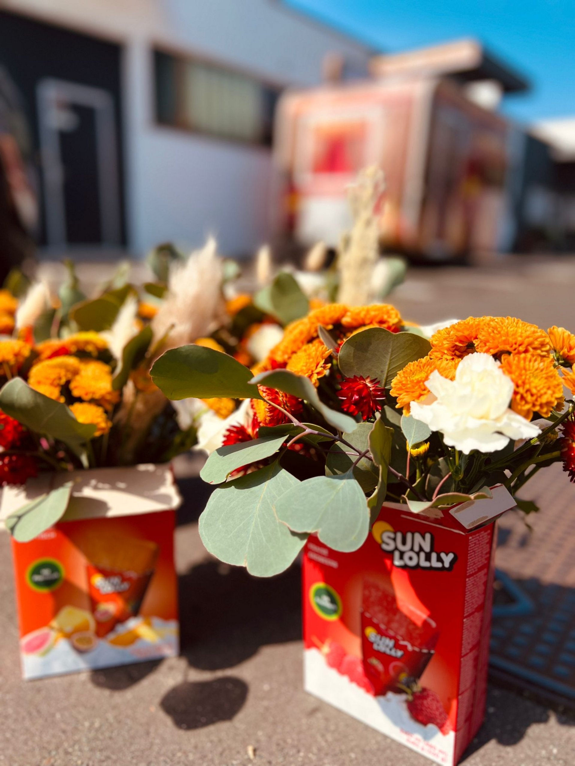 Gelb-weiße Blumengestecke in einer roten Eis-Verpackung beim OEDIV HR Services GmbH Sommerfest