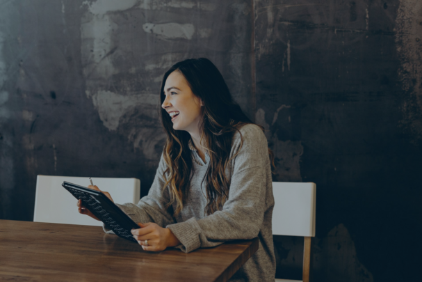 Junge Frau sitzt an einem Tisch mit Tablet in der Hand und bedient die HR Document Box