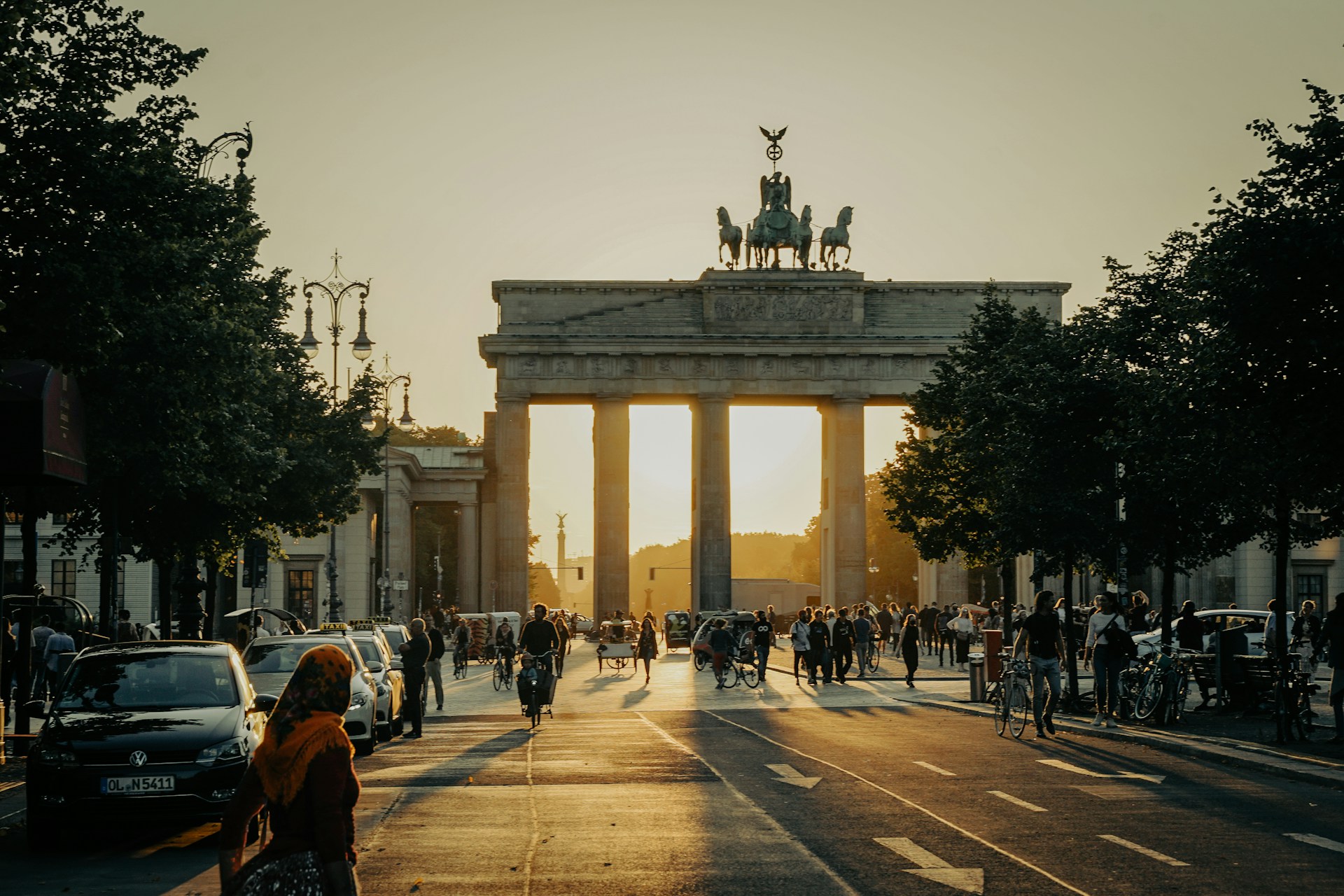 Menschen gehen bei Sonnenaufgang vor dem Brandenburger Tor in Berlin entlang