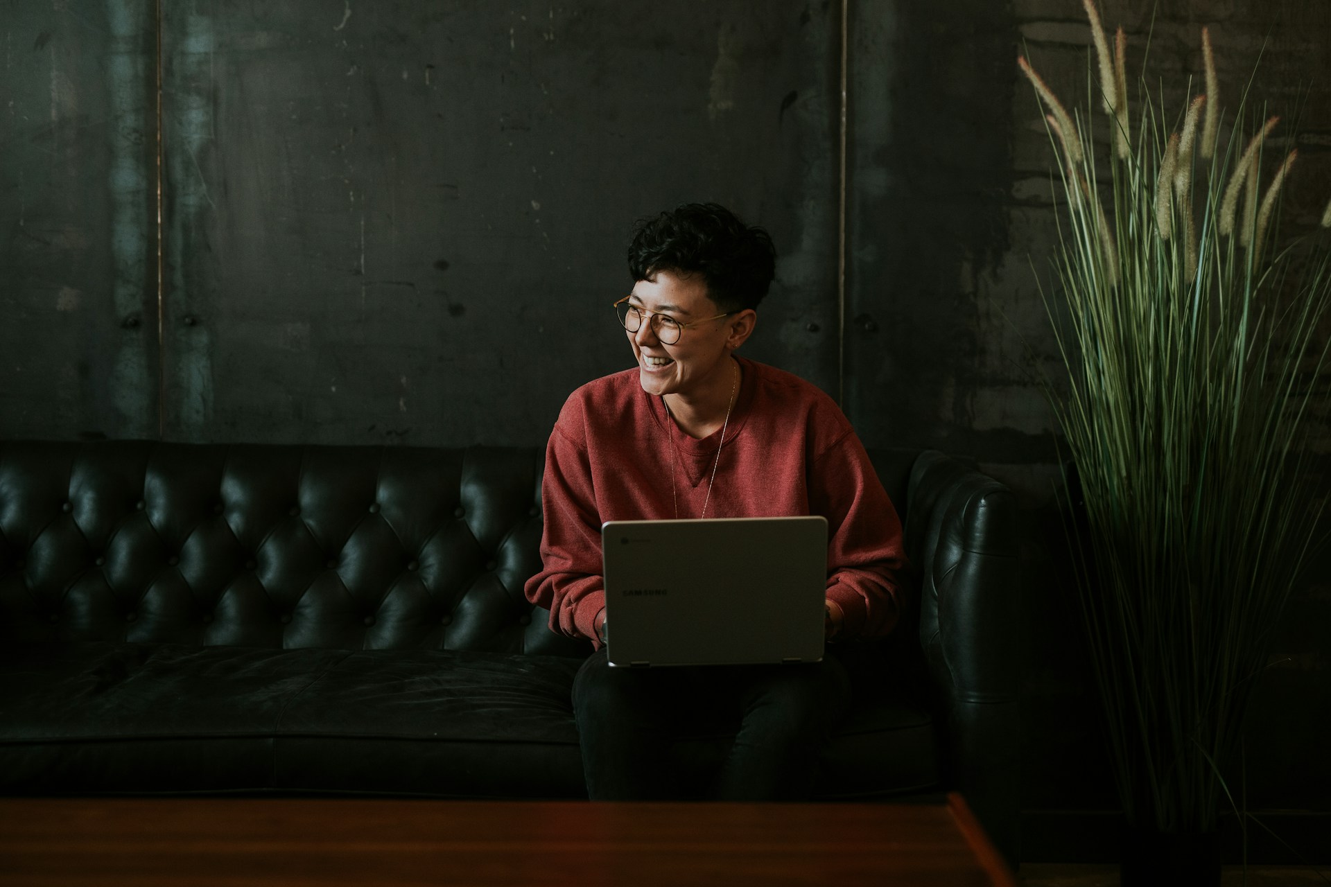 Mitarbeiterin der Personalabteilung sitz mit Laptop auf einem dunklen Sofa